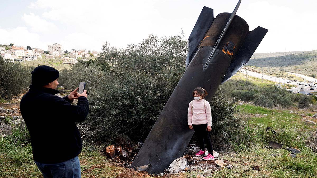 A young girl poses for a photograph in front of an Iranian missile that landed in the village of Kifl Haris in the Israeli-occupied West Bank.